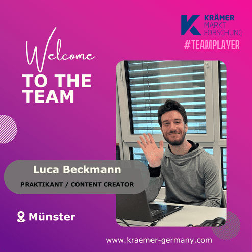 Junger Mann mit braunem Haar sitzt an einem Tisch, winkt mit der Hand und lächelt vor einem Laptop. Textgrafik im Hintergrund.